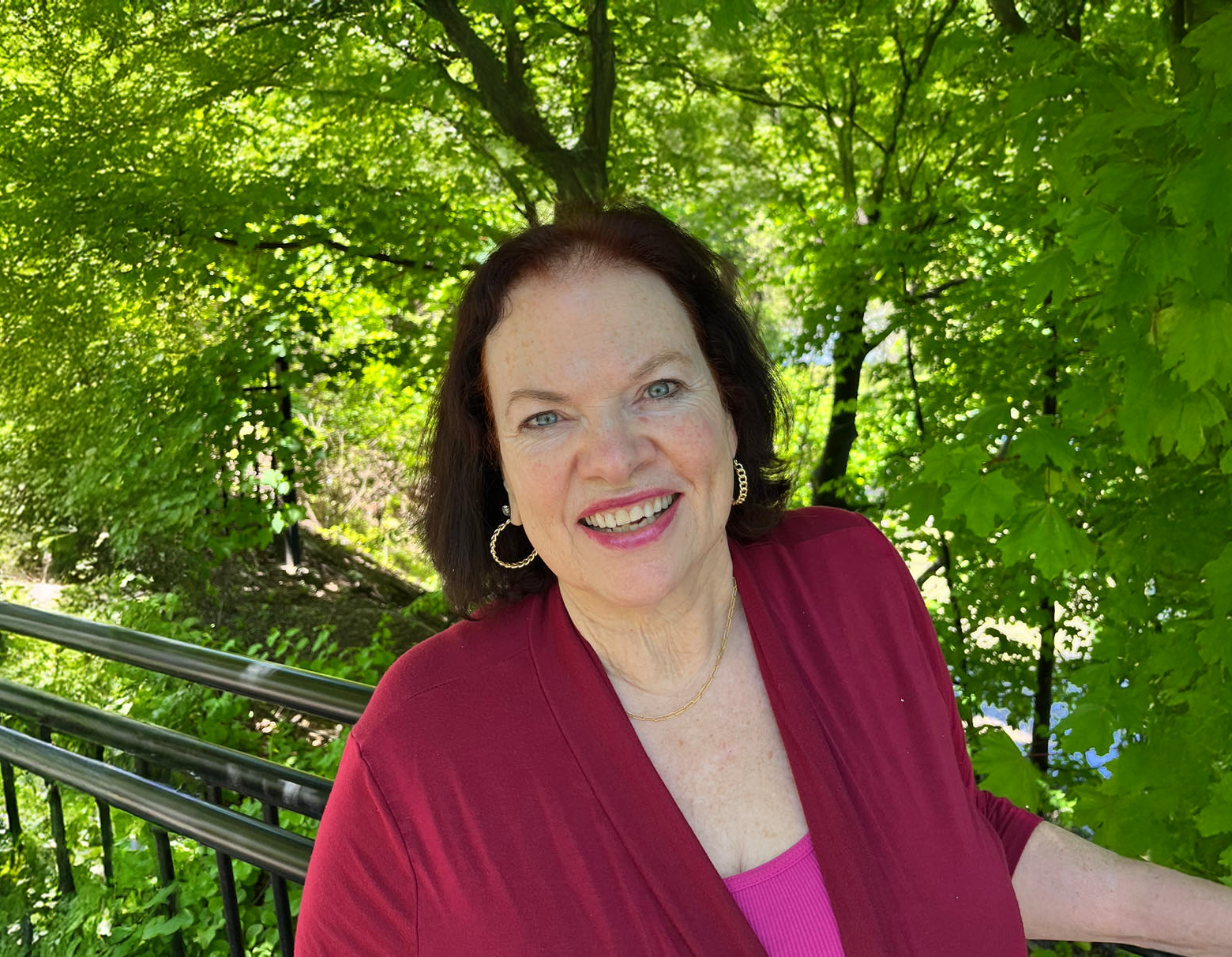 Liz Ryan smiling outdoors under green trees